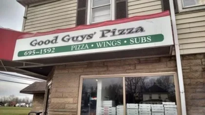 dsfs | Axxcess Platform Exterior view of a pizza shop with a sign reading 'Good Guys' Pizza' and 'Pizza • Wings • Subs'; brick facade and glass door visible.