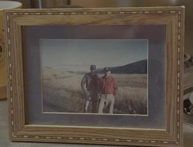 image_desktop 15 | Axxcess Platform Framed photo of two men standing in a field with hills in the background, inside a wooden double-matted frame.