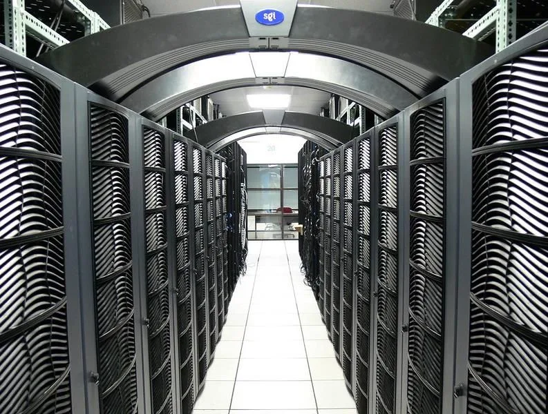 Row of server racks forming a narrow data center aisle with vented black cabinets and a tiled floor, SGI logo overhead.